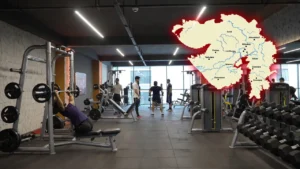 Modern gym interior in India with people working out on treadmills, weights, and cardio machines, overlaid with Gujarat map, representing top fitness and gym franchise opportunities in 2026